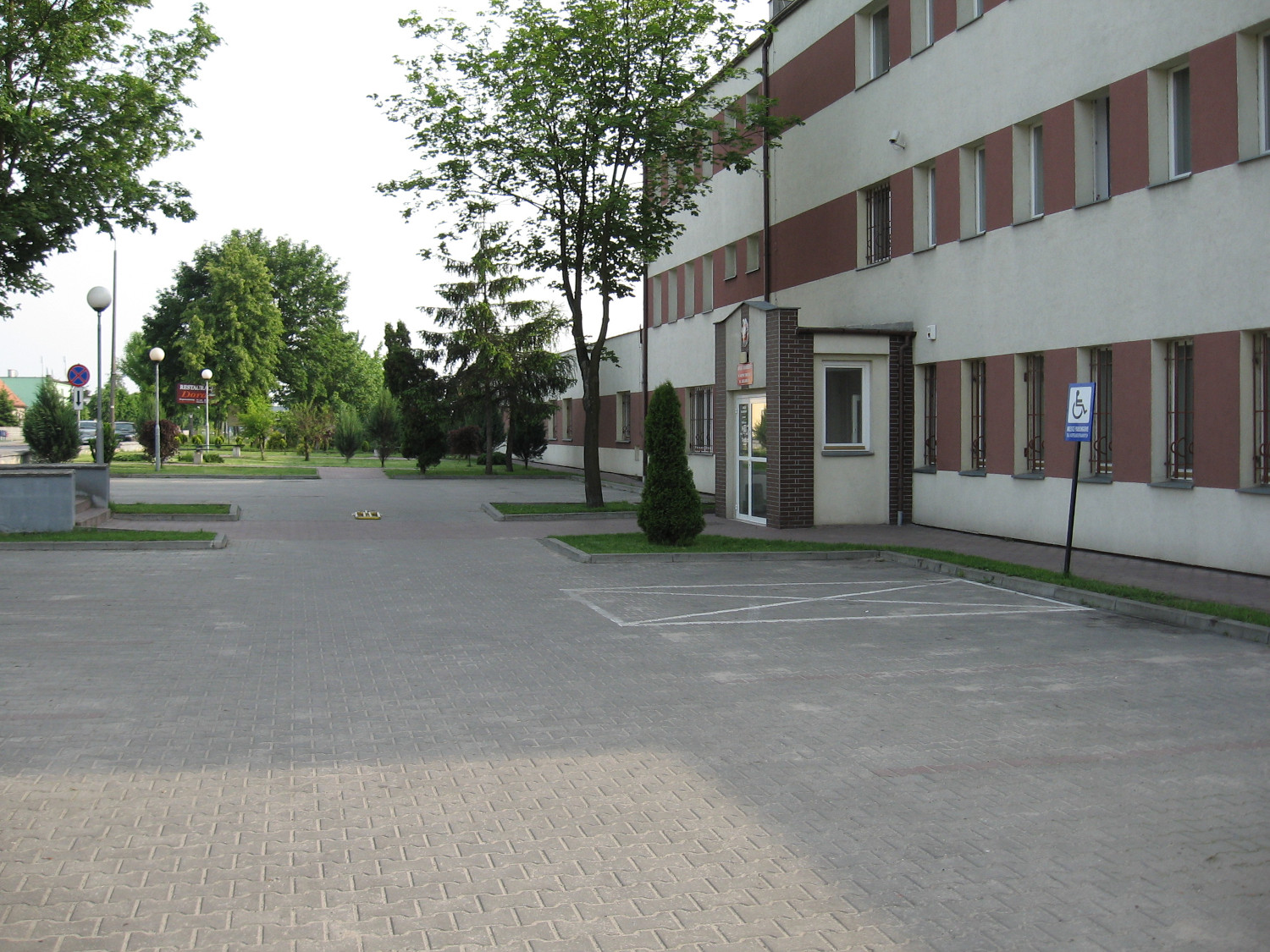 Na zdjęciu budynek w elewacji koloru białego z elementami koloru ceglastego