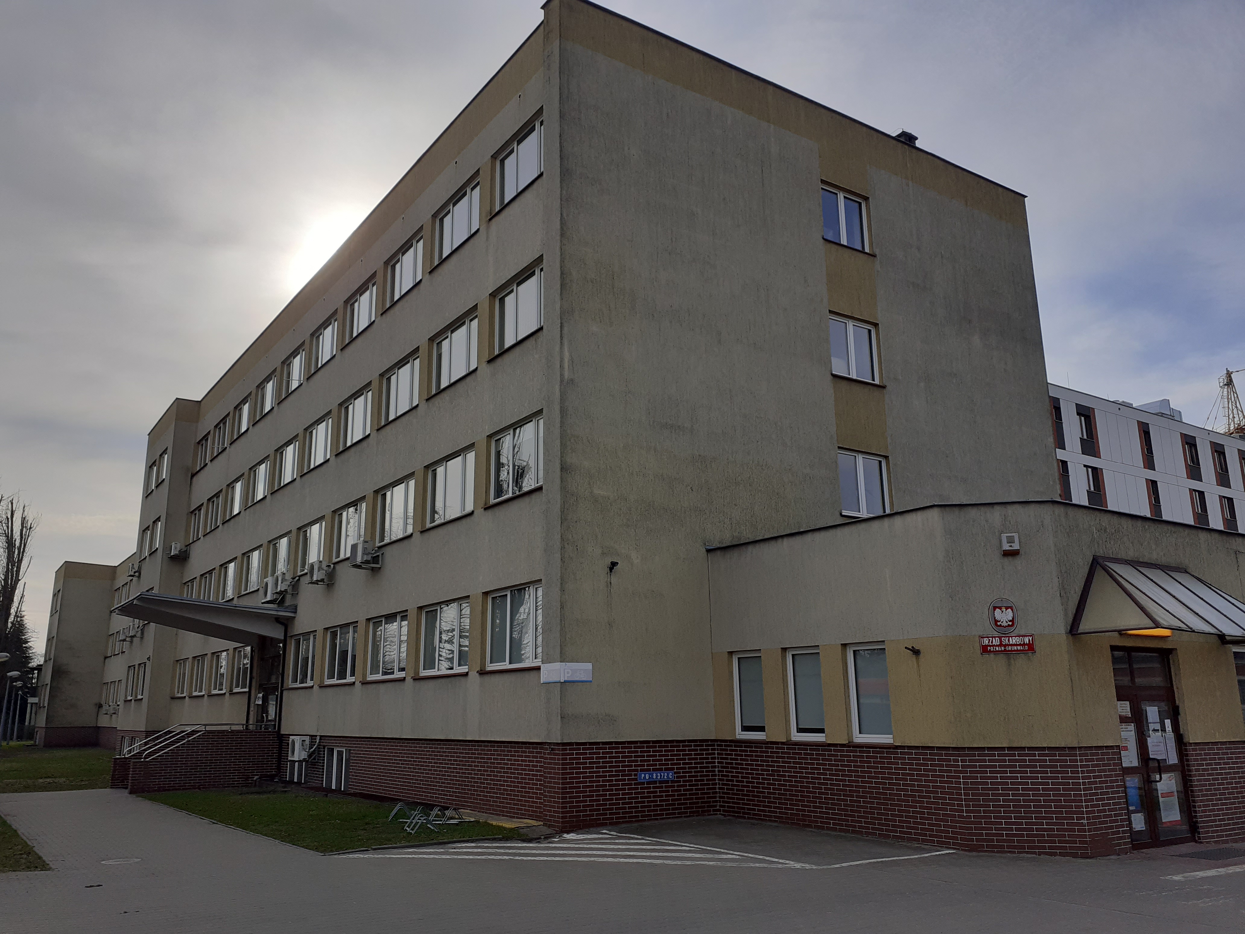 budynek urzędu w szarej elewacji opaska z cegieł wejście boczne bez progów wejście boczne ze schodami