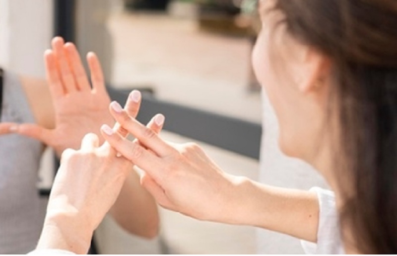 Na zdjęciu pani porozumiewająca się w języku migowym z inną osobą