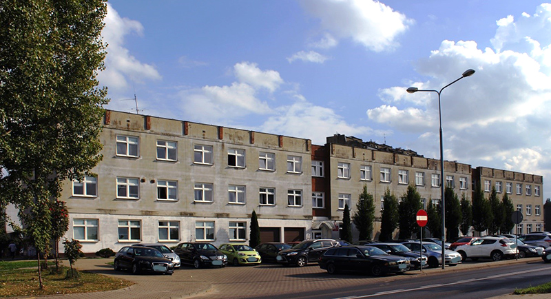 Budynek Pierwszego Urzędu Skarbowego w Radomiu. Przed budynkiem parking i kilka samochodów.