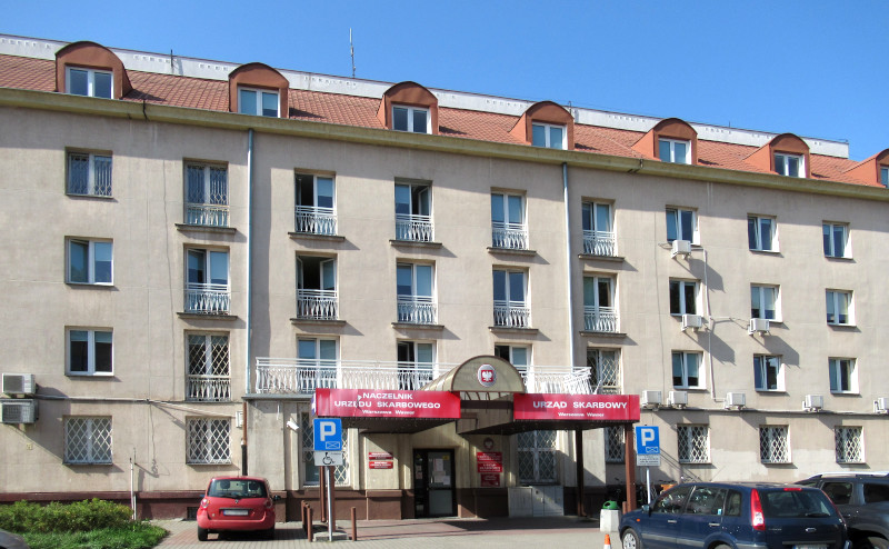 Budynek Urzędu Skarbowego Warszawa-Wawer. Przed budynkiem parking i kilka samochodów.