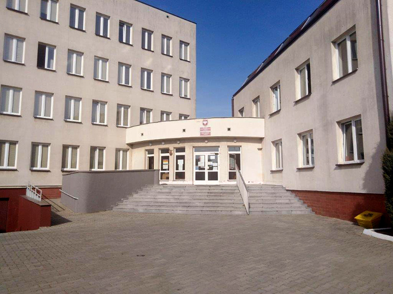 Budynek Urzędu Skarbowego w Grójcu, wejście i schody. Przed urzędem parking.