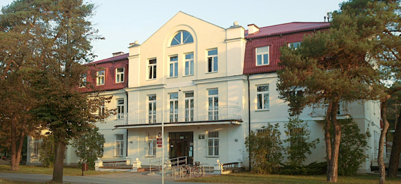 Budynek Urzędu Skarbowego w Otwocku przy ul. Matejki 4. Przed budynkiem krzewy i wysokie drzewa.