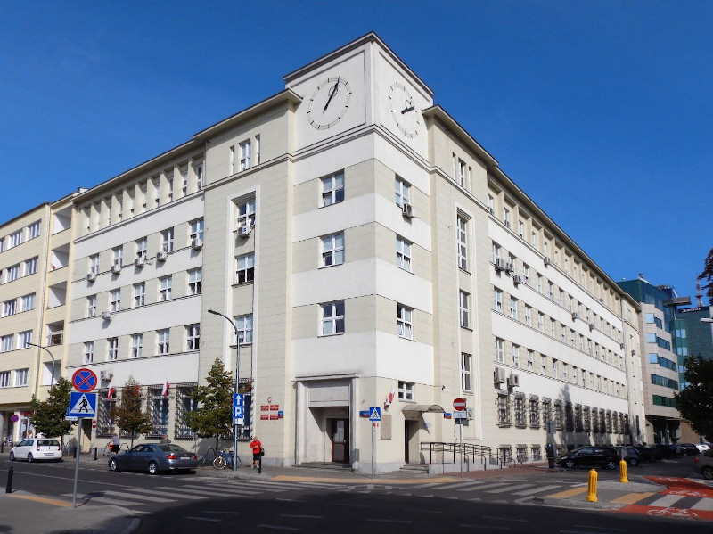 Budynek Trzeciego Urzędu Skarbowego Warszawa-Śródmieście. Przed budynkiem skrzyżowanie dwóch ulic i zaparkowane samochody.