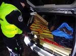 Funkcjonariusz KAS przy samochodzie, w bagażniku którego znajdują się kartony z papierosami