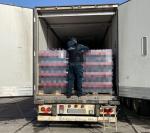 Funkcjonariusz Służby Celno-Skarbowej bada zatrzymane napoje wewnątrz naczepy samochodu ciężarowego
