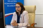 Zdjęcie: Szef Krajowej Administracji Skarbowej Magdalena Rzeczkowska przy biurku przed komputerem podczas spotkania prasowego online