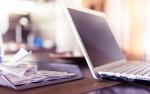na stole leży otwarty laptop, obok kilka paragonów ze sklepów