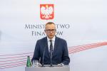 Wiceminister Artur Soboń stoi za mównicą, w tle logo MF