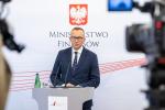 Wiceminister Artur Soboń stoi za mównicą, w tle logo MF