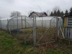 Działka będąca przedmiotem licytacji. Widoczne ogrodzenie, na działce szklarnia z folii. 