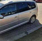 Samochód osobowy VW Touran typu VAN, kolor kremowy metalik. Ciemne szyby tylne. 