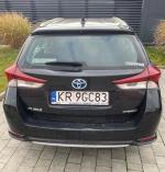 Samochód osobowy Toyota Auris, koloru czarnego. Kombi, częściowo oklejony reklamą. 
