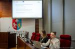 Ekspertki siedzą w sali. Jedna z nich trzyma w ręce mikrofon. Na ekranie wyświetlana jest prezentacja.  Foto: Sebastian Stankiewicz, Biuro Prasowe UMWP.