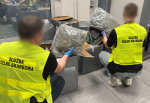 Funkcjonariusze służby celno-skarbowej zabezpieczają duże pakunki z nielegalną marihuaną.