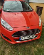 Samochód osobowy marki Ford Fiesta, rok produkcji 2013, benzyna. Przód pojazdu z widoczną tablicą rejestracyjną