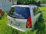 Samochód osobowy Mazda Premacy, kombi w kolorze srebrnym, rok produkcji 2004, wgniecenia w karoserii na nadkolu, tapicerka foteli materiałowa, wyeksploatowane wnętrze z widocznymi przetarciami na kierownicy i fotelu kierowcy.