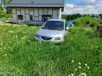 Samochód osobowy Mazda Premacy, kombi w kolorze srebrnym, rok produkcji 2004, wgniecenia w karoserii na nadkolu, tapicerka foteli materiałowa, wyeksploatowane wnętrze z widocznymi przetarciami na kierownicy i fotelu kierowcy.