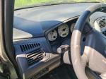 Samochód osobowy Mazda Premacy, kombi w kolorze srebrnym, rok produkcji 2004, wgniecenia w karoserii na nadkolu, tapicerka foteli materiałowa, wyeksploatowane wnętrze z widocznymi przetarciami na kierownicy i fotelu kierowcy.