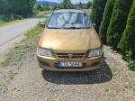 Samochód osobowy Mitsubishi, Space Star, hatchback w kolorze złotym, rok produkcji 1999, tapicerka foteli materiałowa, wyeksploatowane wnętrze z widocznymi licznymi plamami na fotelu kierowcy.