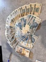 Grafika dekoracyjna, na blacie stolika leżą banknoty w nominałach 50, 100 i 200 PLN, ułożone w wachlarz. Obok leży długopis.